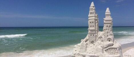 A sandcastle with two towers on a beach.