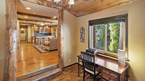A rustic interior with a wooden ceiling, a dining area with a table and chairs, and a kitchen in the background. - Cienega Lakeview by Destination Big Bear : Spectacular Luxury Lakefront! HOT TUB W/Lake and Mountain Views! Game Room with Pool Table! Gourmet Kitchen! (Big Bear Lake)