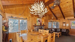 A rustic cabin interior with a wooden dining table, a sofa, and a chandelier. - Walking Distance to Boulder Bay! Lakeviews! PET FRIENDLY! Internet! Darts & Poker Table! (Big Bear Lake)