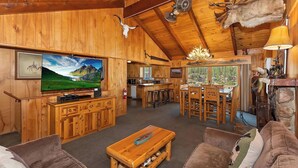 A rustic wooden interior with a large TV, wooden furniture, and a fireplace. - Walking Distance to Boulder Bay! Lakeviews! PET FRIENDLY! Internet! Darts & Poker Table! (Big Bear Lake)