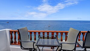 A balcony with two chairs and a table overlooking the sea. - 2B | 2B Villa, OCEAN VIEWS, NO STEPS, Golf Cart, 2 private balconies, electric f (Avalon)