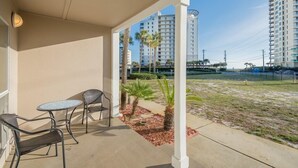 A covered outdoor area with a table and chairs, palm trees, and a view of high-rise buildings.