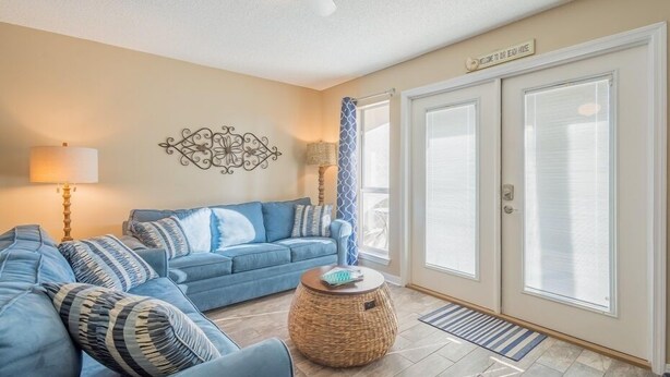 A living room with a blue sofa, a round wicker coffee table, and a ceiling fan.
