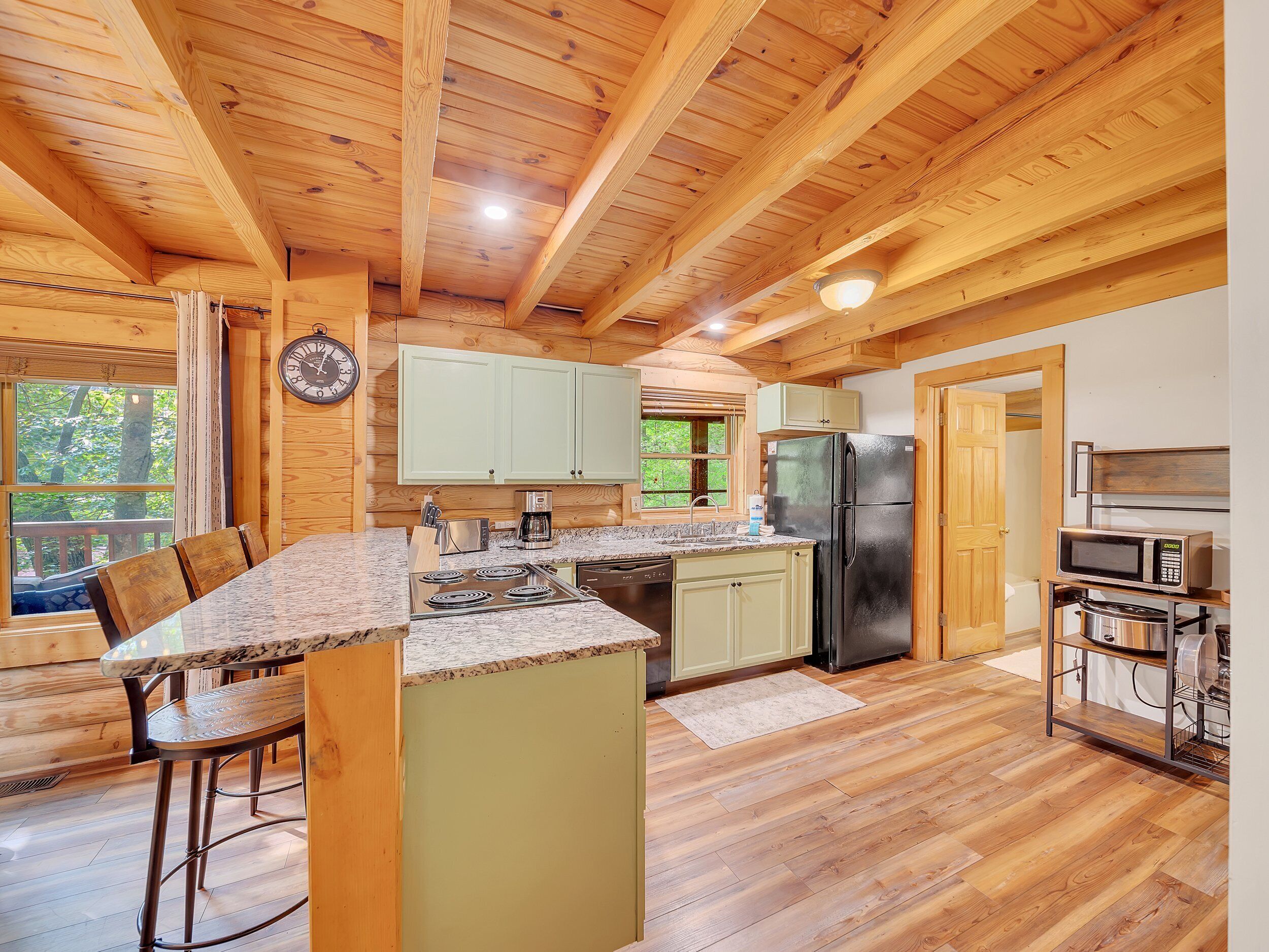 L’intérieur d’une cabane en bois comprend une cuisine avec un îlot central, une cuisinière, un réfrigérateur et un four à micro-ondes.