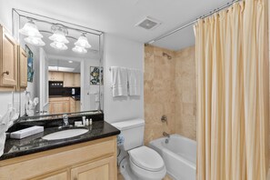 A bathroom with a sink, toilet, bathtub, and shower curtain.