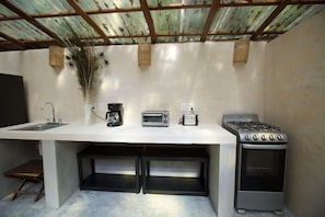 A compact kitchen with a gas stove, a coffee maker, a toaster, and a sink. - Magical jungle Eco Cabana in Tulum Mexico (Macario Gómez)