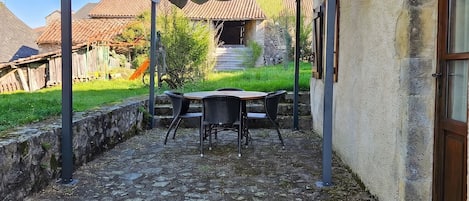 Un patio con mesa y sillas, una pérgola y un muro de piedra.