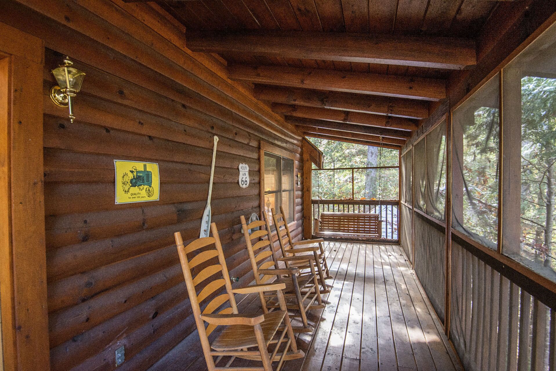 Une cabane en bois avec une véranda, des chaises en bois et un panneau indiquant la Route 66.