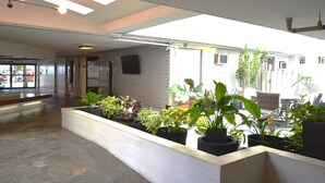 A spacious lobby with a modern design, featuring a reception desk, seating area, and potted plants.