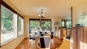 Une cuisine spacieuse dotée de grandes fenêtres, d’un plancher en bois et d’un coin repas avec des chaises et une table.