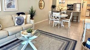 Una sala de estar con sofá, mesa de centro y una zona de comedor con sillas y una mesa.