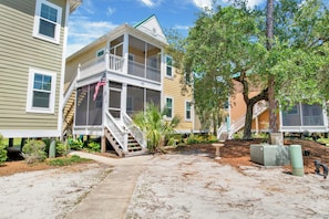 A residential area with two-story houses, a covered porch, and a tree. - Purple Parrot Condo Near Beach with Pool (Pensacola)