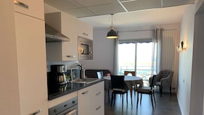 A modern kitchen with a dining area, featuring a built-in oven, microwave, and coffee maker.