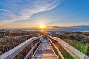 A wooden boardwalk leading to a sunset over a marshy landscape. - Great views, swimming pool, boardwalk to the beach, picnic tables, play area, co (Port Aransas)