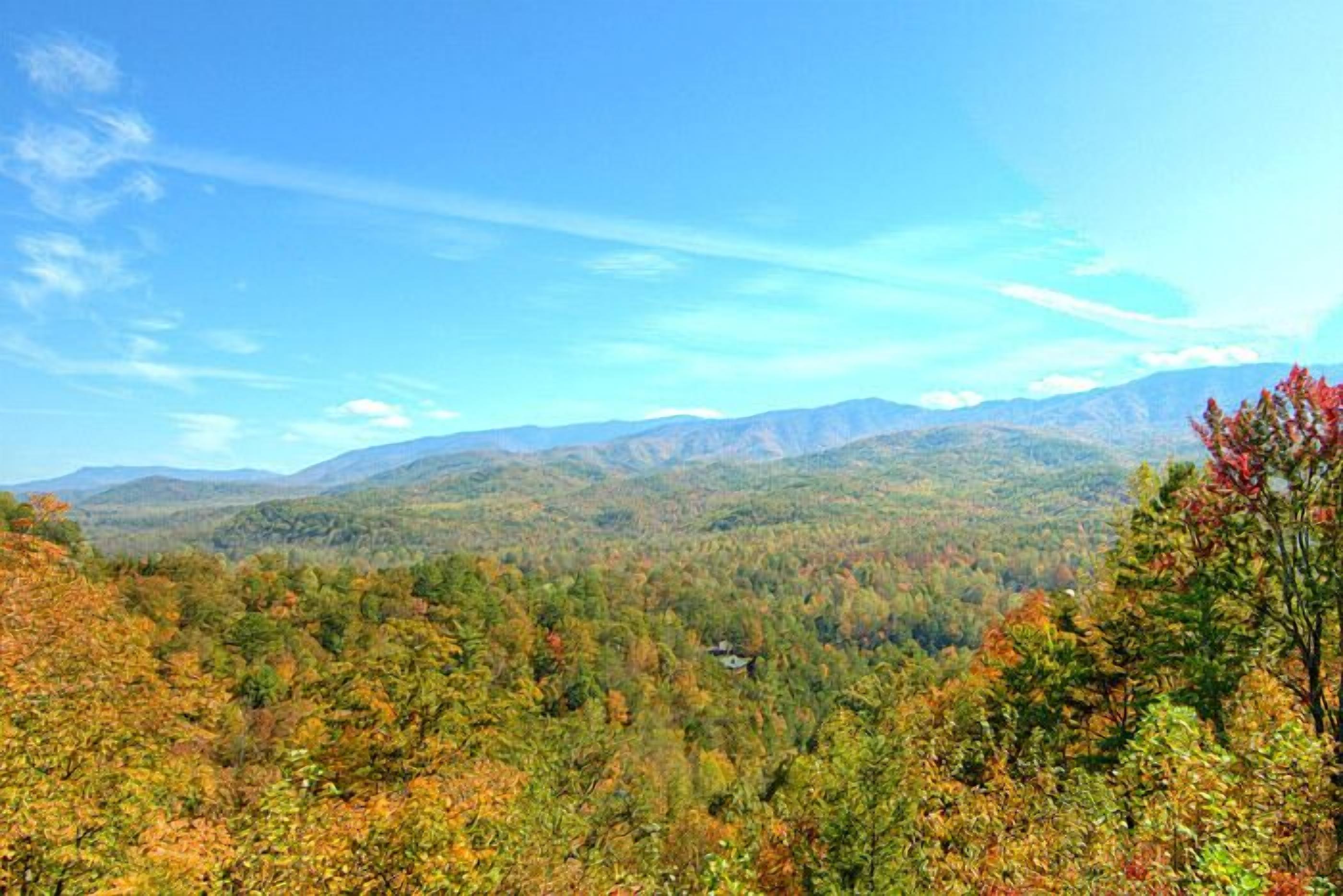 Un paysage montagneux aux couleurs automnales, sous un ciel dégagé.