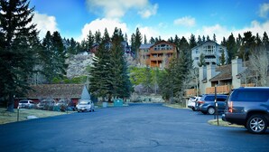 A residential street with houses, parked cars, and a clear sky.