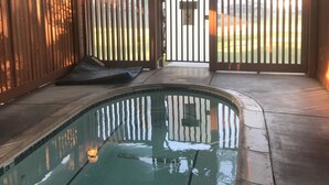 An indoor swimming pool with a tiled floor, wooden deck, and a gated entrance.