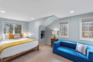 Een slaapkamer met een bed, een blauwe bank en een nachtkastje met een lamp.