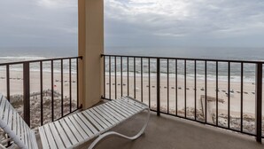 Un balcon avec un banc blanc donnant sur une plage de sable fin et l’océan.