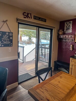 Una habitación con puerta de vidrio corredera que da a una terraza exterior, una mesa de madera y un letrero que dice "SKI PURGATORY".