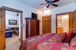 A bedroom with a large bed, wooden wardrobe, a ceiling fan, and a television on a stand. - 2109 Timberline Lodge, Trappeur's Crossing Apartment 1 (Steamboat Springs)