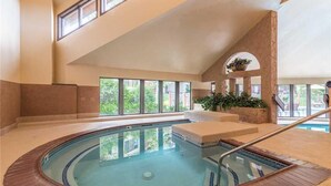Ein Hallenbad mit einer gefliesten Kante, einem Holzboden und einer Steinwand.