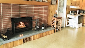 A kitchen with a brick fireplace, wooden cabinets, and a sign that reads "LAKE RULES".