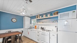 Une cuisine moderne avec des meubles blancs, une table à manger en bois et un mur d’accent bleu.