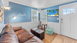 Une pièce avec un mur bleu, un canapé en cuir marron, une petite table, une chaise et une porte.