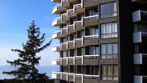 Um edifício residencial com várias andares, varandas, janelas amplas e um céu claro.