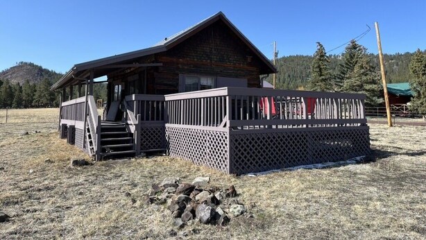 A wooden cabin with a porch and a fenced deck.