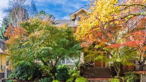 A residential house with a front porch, steps, and a variety of trees in autumn colors. - Beautiful Irvington Apartment near City Center! (Portland)
