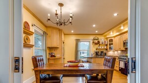 A spacious kitchen with wooden cabinets, a dining table with chairs, and a chandelier. - Beautiful Irvington Apartment near City Center! (Portland)