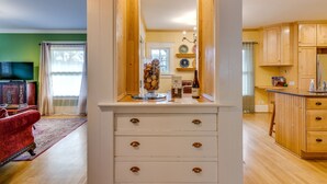 A kitchen with wooden cabinets, a countertop, and a dining area with a red sofa. - Beautiful Irvington Apartment near City Center! (Portland)