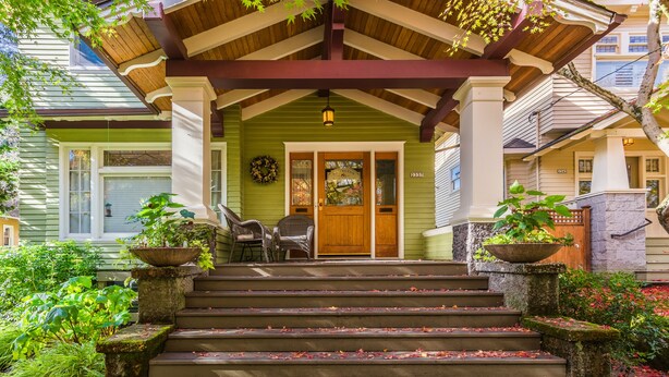 A porch with a wooden bench and a door, surrounded by a garden with stone steps and plants. - Beautiful Irvington Apartment near City Center! (Portland)