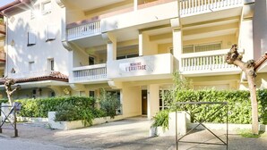 Un edificio residencial de varios pisos con balcones, un cartel que dice "RESIDENCE L'ERMITAGE" y un camino de entrada de grava.
