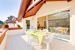 A patio with a table set for dining, white chairs, and a wooden ceiling. - HOSSEGOR Downtown, sleeps 4 (HOSSEGOR)