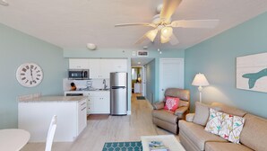 Un espacio habitable compacto con kitchenette, comedor, sofá y ventilador de techo.
