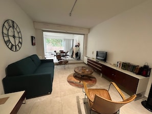 A living room with a sofa, a coffee table, a TV, and a bookshelf.