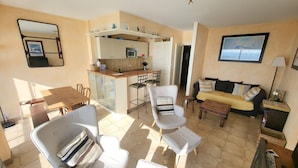 A compact living space with a kitchenette, a dining area, and a seating area with a sofa and chairs. - 2-Bedroom Apartment Sea View - Parking, Pets Allowed (Les Sables-d'Olonne)