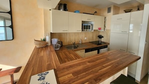 A compact kitchen with wooden countertops, white cabinets, a microwave, and a coffee maker. - 2-Bedroom Apartment Sea View - Parking, Pets Allowed (Les Sables-d'Olonne)
