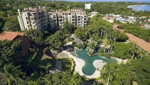 Ein Resort mit einem großen Gebäude, einem Schwimmbad und üppiger Vegetation.