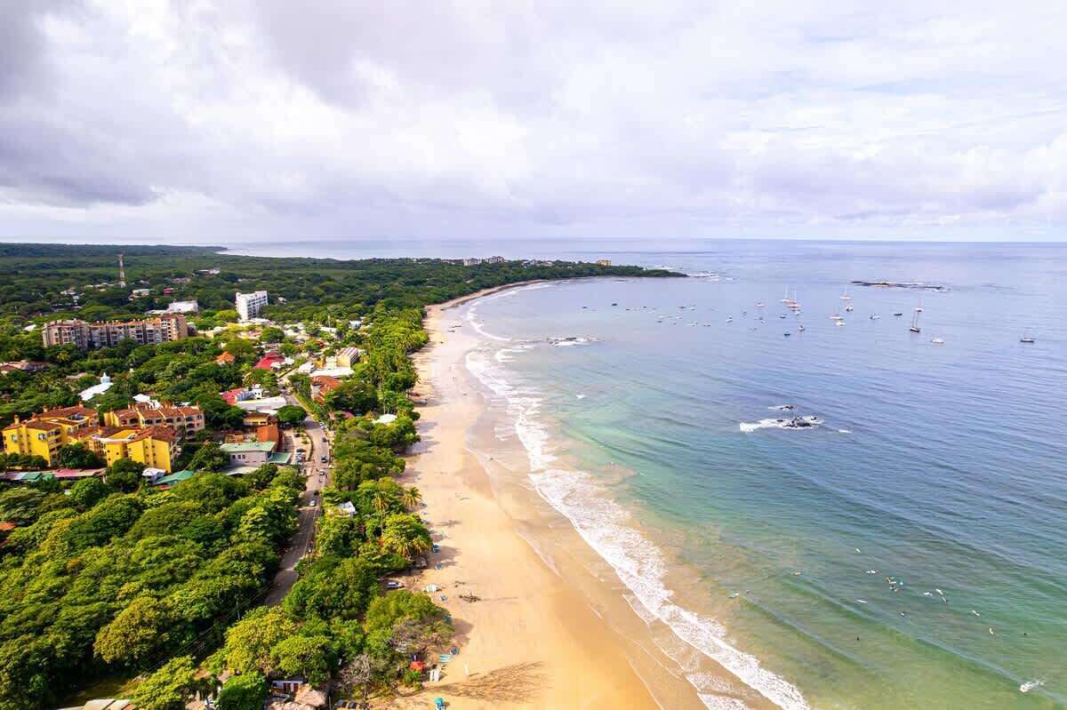 Zona costera con playa, edificios y barcos.
