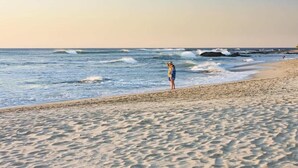 Ein Strand mit einer Person, die am Sand nahe dem Wasser steht.