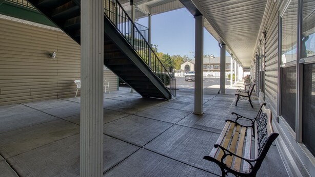 Un espace extérieur abrité, doté d’un escalier, de bancs et offrant une vue dégagée sur la rue.