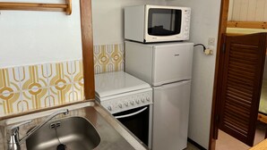 A compact kitchenette with a sink, a microwave, a small refrigerator, and a stove.