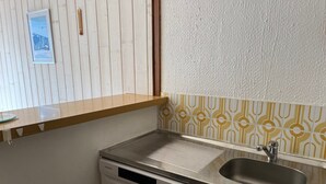 A compact kitchen with a stainless steel sink, a dishwasher, and a wooden countertop.