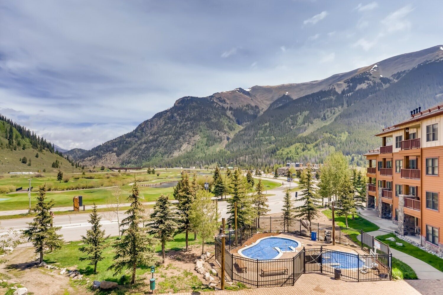 Un hôtel doté d’une piscine, entouré de montagnes et de verdure.