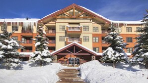 Ein mehrstöckiges Hotel mit zentralem Eingang, Balkonen und verschneiter Umgebung.