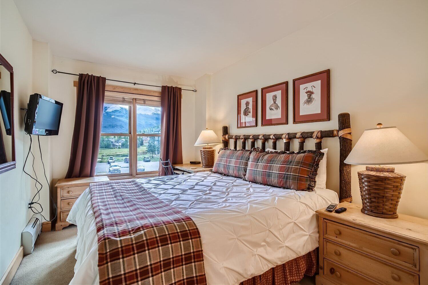 Een slaapkamer met een groot bed, twee nachtkastjes, een televisie en een raam met gordijnen.